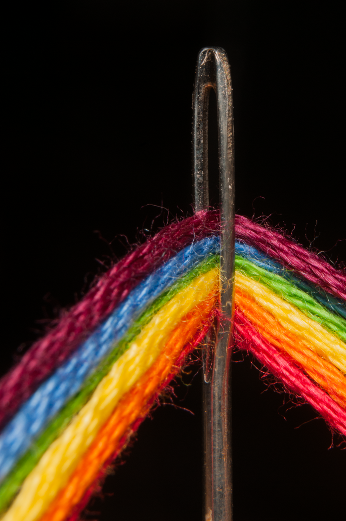 The Art of Drawing Readers In: Your attractive post title goes here Vibrant close-up of a sewing needle threaded with colorful rainbow yarn.